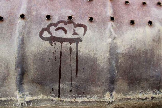 Raincloud painted with water on a rusted drum. drying quickly.