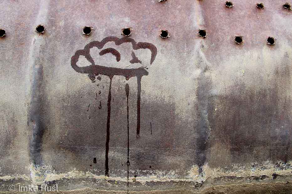 Raincloud painted with water on a rusted drum. drying quickly.